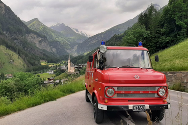 Rotes Opel-Feuerwehrfahrzeug mit Blaulicht vor alpiner Berglandschaft. | © Freiwillige Feuerwehr Pottenstein 