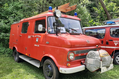 Historisches rotes Feuerwehrfahrzeug (Opel Blitz) mit Blaulicht und Dachleiter, geparkt auf einer Wiese. | © Feuerwehr Elsbach 