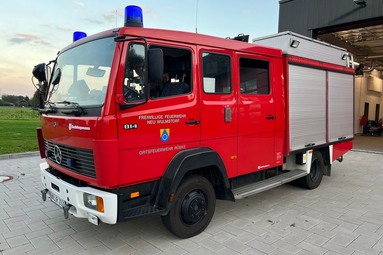 Rotes Feuerwehrfahrzeug (Löschfahrzeug) der Freiwilligen Feuerwehr, seitlich vor einer Fahrzeughalle geparkt, mit blauem Blinklicht auf dem Dach und Geräteraum im hinteren Aufbau. | © Freiwillige Feuerwehr Rübke 