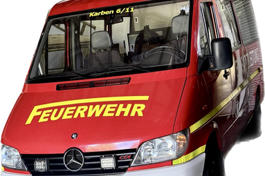 Roter Feuerwehr-Transporter (Mercedes-Benz) mit gelber Aufschrift „FEUERWEHR“ auf der Motorhaube, Frontansicht schräg von links; Blaulichter auf dem Dach und reflektierende Streifen an der Seite sichtbar. | © LF16 Petterweil 