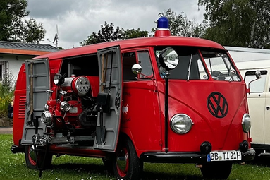 Roter historischer Volkswagen-Feuerwehrbus mit Blaulicht und geöffneter Seitenklappe, der eine eingebaute Löschpumpe zeigt. | © Swäbisch-Ungarisches Feuerwehr Museum