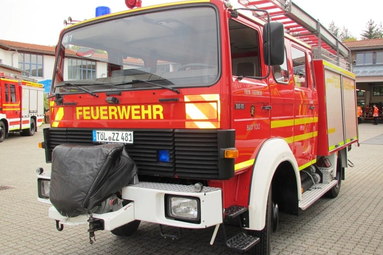 Modernes rotes Feuerwehrfahrzeug mit gelber „Feuerwehr“-Beschriftung und Dachleiter, geparkt auf einem Feuerwehrgelände. | © Freiwillige Feuerwehr Bad Tölz 