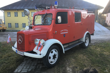 Historisches rotes Feuerwehrfahrzeug der Feuerwehr Frankenmarkt, auf einem Hof vor Gebäuden geparkt, mit klassischer Frontpartie, Blaulicht und traditioneller Ausrüstung. | © Feuerwehr Oldtimer Verein Frankenmarkt 