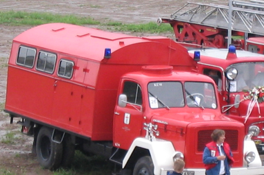 Historisches rotes Feuerwehrmannschaftsfahrzeug mit großem Aufbau und Blaulicht, auf einem Veranstaltungsgelände neben weiteren Einsatzfahrzeugen ausgestellt. | © TLFA 4000 Kitzbühel 